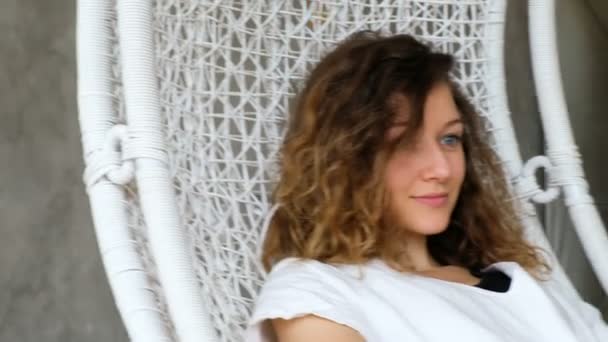 Bir çatı katı daire hızıyla hamak bir genç Avrupa Kız portresi. Dinlenme ve bir hamak koltuğu sallanan güzel kadın — Stok video
