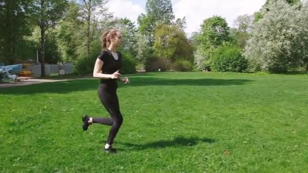 schönes junges Mädchen mit langen Zöpfen, die im Park herumlaufen, gesunder Lebensstil. Europäische Frau trainiert im Park, Zeitlupe