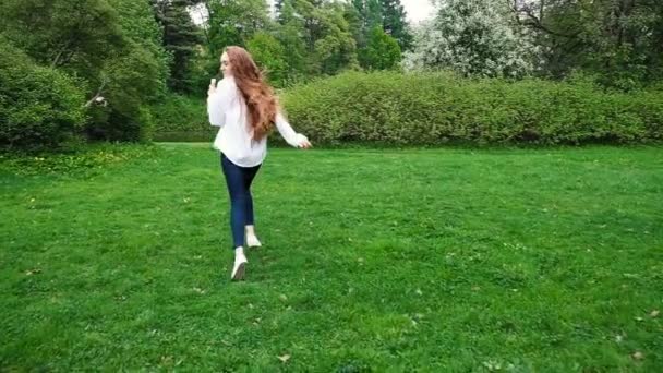 Europäisches Mädchen mit langen lockigen Haaren, das im Park mit Seifenblasen rennt. sehr lange Haare flattern im Wind, Zeitlupe — Stockvideo