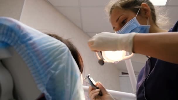 Jovem dentista está tratando e perfurando dentes para um paciente. Na recepção no doutor do stomatologist — Vídeo de Stock