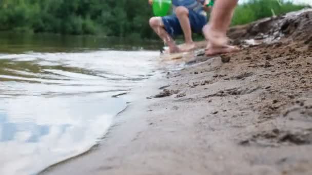 Patas infantiles borrosas. Niños jugando en el río con arena — Vídeos de Stock