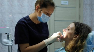 Diş hekimi ortodontist diş fiksatör için köşeli ayraç sistemini yüklemek bir kadın koyar. Dişçiye ziyaret