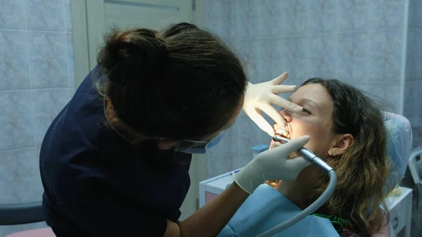 Orvos befejezi a kezelés. Látogasson el a fogorvoshoz. Fogorvos őröl, és tisztítja a fogakat tartó rendszer telepítése előtt. — Stock Fotó