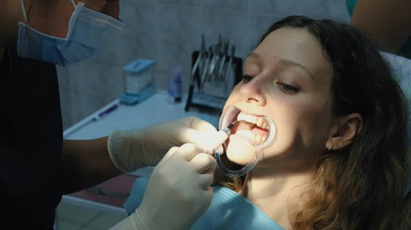 Dentista aplica cola ortodôntica sobre os dentes para a mulher na trava antes de instalar o sistema de suporte. Visita ao estomatologista ortodontista . — Fotografia de Stock