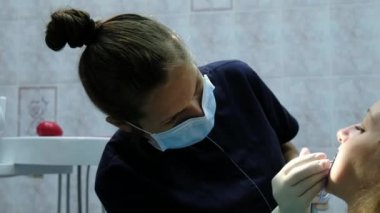 Diş hekimi temizler ve bir yakın çekim anten sistemi yüklemeden önce diş iyileştiriyor. Ortodontist için ziyaret edin