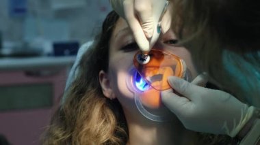 Diş hekimi asistanı Uv lambası hastalar dişlerde bir polimerizasyon ile parlar. İçin stomatologist ziyaret edin