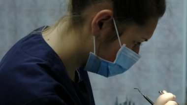 Diş hekimi, anten sistemi kurulumu ve maloklüzyon düzeltilmesi için ziyaret edin. Ortodontist ayarlama aparatı düzeltir ve diş ayna yakın çekim görünüyor.