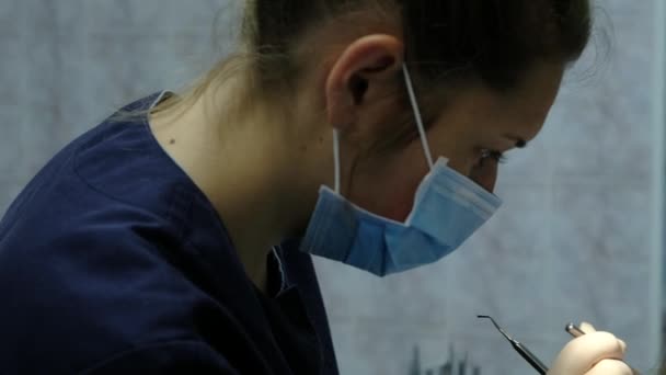 Bezoek aan de tandarts, de installatie van het systeem van de beugel en correctie van de malocclusie. Orthodontist corrigeert de set beugel en kijkt in de tandheelkundige spiegel close-up. — Stockvideo