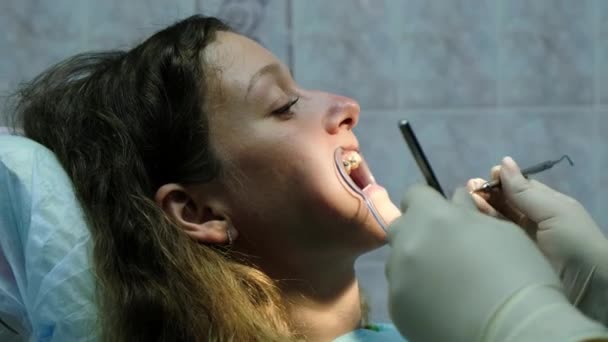 치과, 브라켓 시스템의 설치에 방문. 환자 클로즈업에 중괄호에 치과 합 자외선 램프와 함께 도우미 빛난다. — 비디오