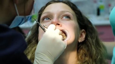 İçin düzeltme maloklüzyon, tedavi diş hekimine. Ortodontist yüklü ayraçlar içinde ayna yakın çekim denetler.