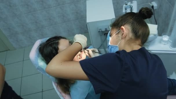 Bezoek aan de tandarts. Orthodontist arts stelt ijzeren beugels voor een vrouw met een tandheelkundige fixatiemiddel, bovenaanzicht — Stockvideo