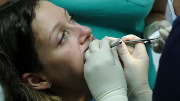 Відвідування стоматолога. Ортодонт встановлює залізні брекети жінці і працює з інструментами в роті крупним планом . — стокове відео