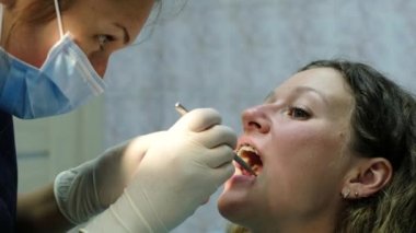 Diş hekimine, köşeli ayraç sisteminin kurulumu ziyaret edin. Ortodontist yüklemeyi tamamlar, hastanın diş ağrısı var.