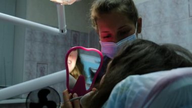 Ziyaret ve danışmanlık dişçi, diş telleri kurulumu. Ortodontist söyler ve tedavi planı açıklar, hasta ayraçlar aynaya bakar