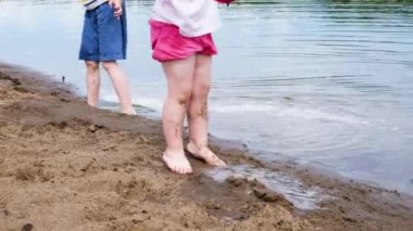 Küçük kız ve erkek bir kova, yavaş hareket ile nehirden su çizin. Sahilde kum doğada çocuk oyun