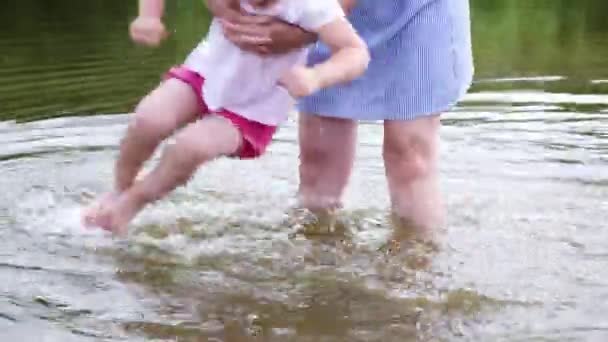 Mother of the little girl washes his feet in the river. Woman playing with her baby on the beach — Stock Video