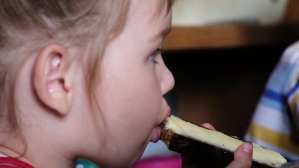 La niña está comiendo un sándwich con mantequilla y engañando de cerca — Vídeos de Stock