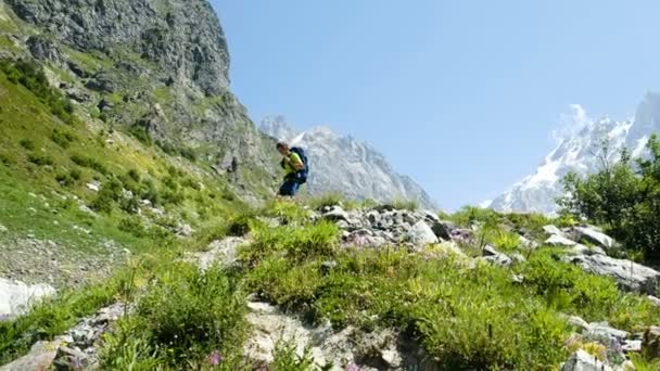 Yorgun turist rota geçtikten sonra dağdan iner, elinde kamerayla kapatır. Adam bir sırt çantası ile geri dağlardan geliyor. — Stok video