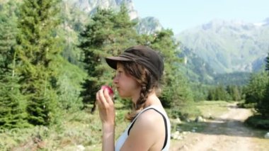 Genç kadın turist dağlarda yürüyüşe üzerinde bir elma yemek. Meyve bir doğa gezisi Avrupa kız aperatifler