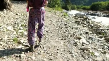 Trekking botları bir sırt çantası ile genç kadın turist yürümek bir arka plan güzel dağ sahne kamera hareketi bir dağ nehir boyunca uzun bir yürüyüş içinde