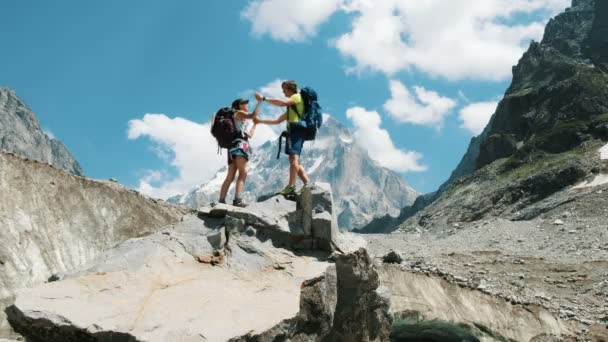 Amante pareja de turistas con mochilas en la caminata beso en la cima de las montañas. El concepto de amor, logro de la meta y éxito — Vídeo de stock