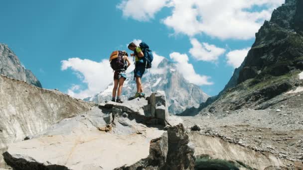 Familie paar toeristen met rugzakken in de wandeling naar het verwijderen van rugzakken op de top in de bergen. — Stockvideo