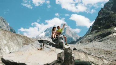 Birkaç turist kayanın üzerinde oturmak ve bir harita çalışma, bir rota bir dağ yürüyüş içinde.