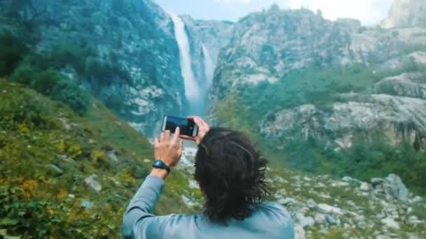 Пішохідний мандрівник фотографує на смартфоні водоспаду в горах крупним планом . — стокове відео