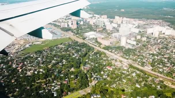 Vue depuis la fenêtre d'un hublot survolant la ville et les maisons, au ralenti. Silhouette et ombre d'un avion — Video