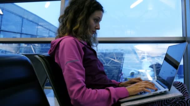 Mujer turista freelancer escribiendo en el portátil, esperando avión y vuelo en el aeropuerto en la sala de espera — Vídeo de stock