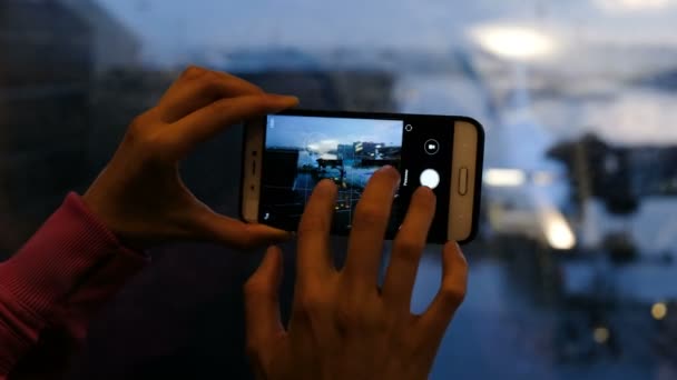 在机场的女人拍一张飞机的照片通过一个玻璃上的智能手机特写 — 图库视频影像
