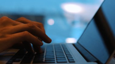 Bir uçak havaalanında bekleme odasında açılış için bekleyen bir dizüstü bilgisayar klavye yakın çekim, serbest meslek sahibi kadın yazdırır