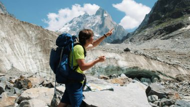 Turist adam üstünde belgili tanımlık harita ve telefon Gps, rota keşfetmek bir sırt çantası ile bir harita ekler ve dağ zammı bir rotada devam ediyor