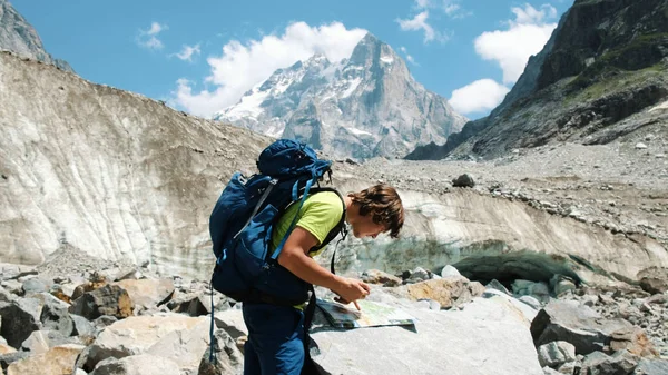 Útikalauz egy ember, egy hátizsák az útvonal a térképen, és a hegyi túra Gps telefon tanul — Stock Fotó