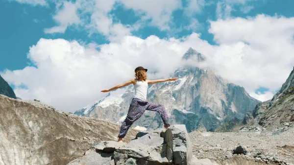 Mulher executa um asana básico em ioga em um fundo de montanha de neve em uma caminhada. Menina faz ginástica no ar fresco em uma caminhada na natureza — Fotografia de Stock