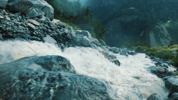 Быстрый поток течет в горах, движение камеры. Всплески, разбивающиеся о камни — стоковое фото