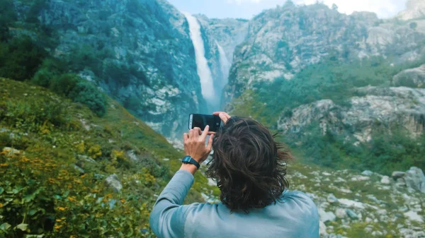 Путешественник фотографируется на смартфоне водопада в горах крупным планом . — стоковое фото