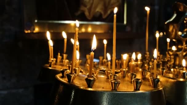 Kvinna lyser ett vaxljus i ett rökelsekar i en ortodox katolsk antika tempel — Stockvideo
