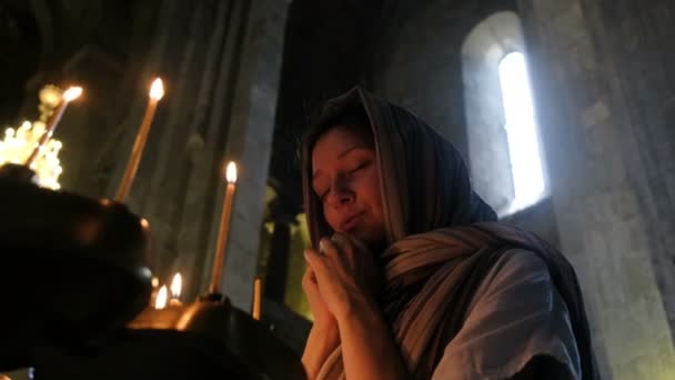 Γυναίκα στην ισλαμική μαντίλα προσεύχεται πριν από ένα εικονίδιο στο την Ορθόδοξη καθολική εκκλησία — Αρχείο Βίντεο