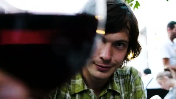 Man op een datum clinks van een glas wijn met een meisje en neemt een slokje in een restaurant, close-up. — Stockvideo