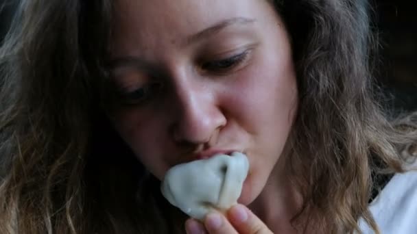 Женщина ест хинкали с мясом в ресторане. Молодая девушка ест грузинский шпинат крупным планом . — стоковое видео