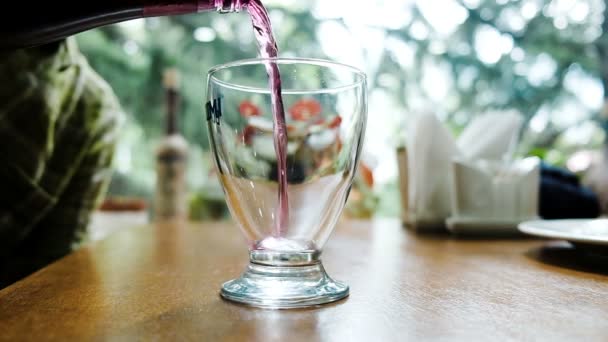 Mann gießt Traubenlimonade aus Flasche in einem Restaurant in ein Glas, Nahaufnahme. — Stockvideo