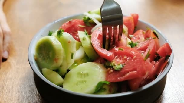 La mujer come una ensalada de verduras frescas pepinos y tomates en un tenedor, concepto de nutrición adecuada, comida vegetariana saludable de cerca. Movimiento lento — Vídeo de stock