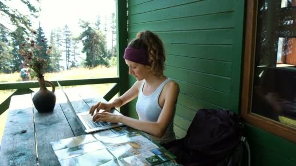 Woman tourist prints a route on a laptop, writes a report on a hike outdoors in summer — Stock Video