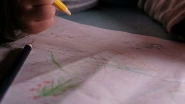 Kleine kind tekent op een vel papier met potloden en viltstiften, leert om te tekenen op een stuk papier - thuis onderwijs. — Stockvideo