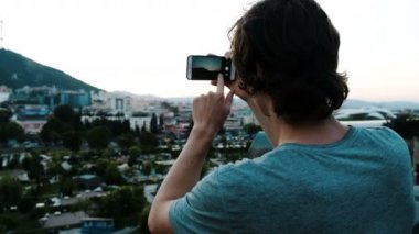 Adam turist gözlem güverte şehirden tarihsel bir yerde bir smartphone panorama fotoğraf çekimi.