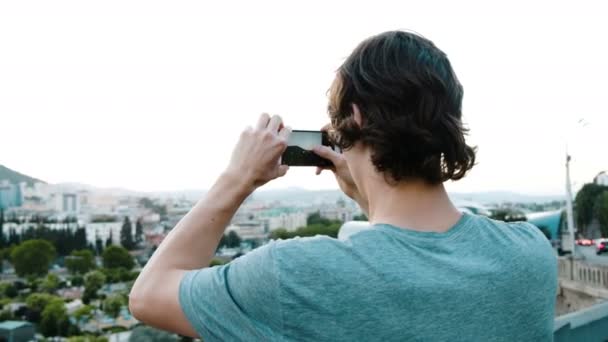 Tourist fotografiert einen historischen Ort in der Stadt von einer Aussichtsplattform aus mit dem Smartphone. — Stockvideo