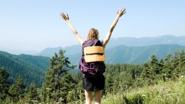 Kadın turist bir sırt çantası ile elleri yukarı yükseltir ve güzel dağ manzarası arka planı mutluluktan bir yürüyüş sırasında atlar. Başarı, hedef başarı ve zafer kavramı. — Stok video