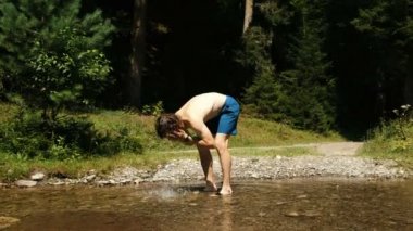 adam yıkar ve ormanın bir dağ dere dururken soğuk suda temperli.