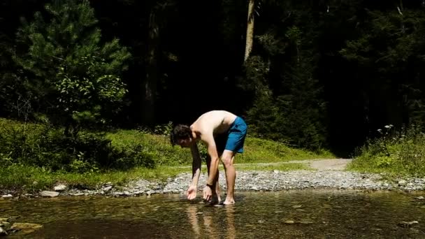 男は洗浄と森林、スローモーションの渓流に立ちながら冷たい水で鍛えています。 — ストック動画